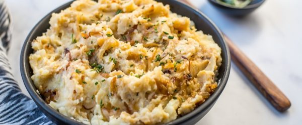 A Creamy Bowl of Rosemary Mashed Potatoes Sits Beside a Wooden Spoon and Fresh Rosemary Sprigs.