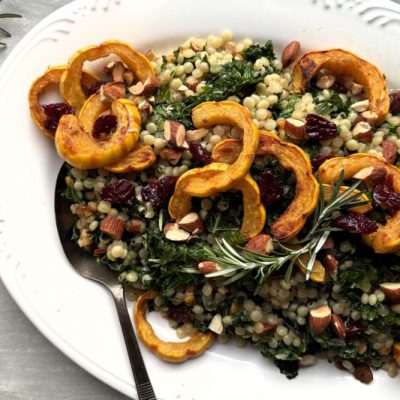 Toasted Couscous with Almonds, Wilted Greens, Tart Dried Cherries and Roasted Delicata Squash Piled on an Oval Serving Platter for a Holiday Feast