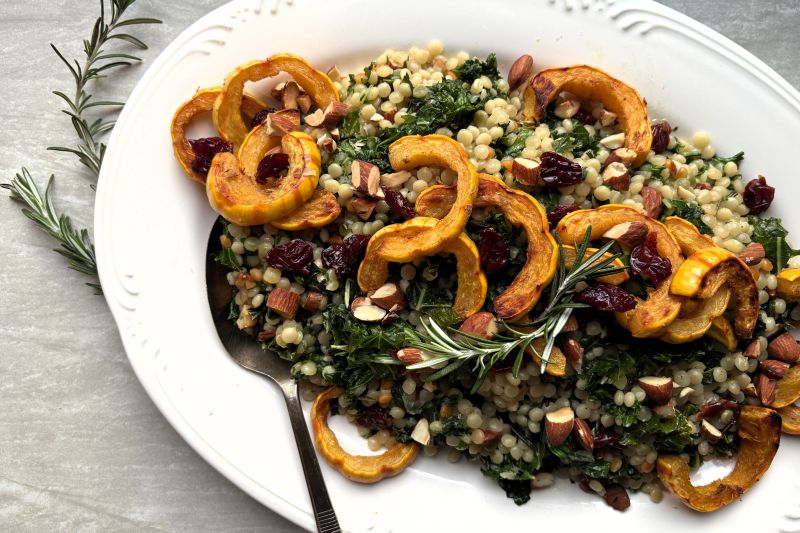 Toasted Couscous with Almonds, Wilted Greens, Tart Dried Cherries and Roasted Delicata Squash Piled on an Oval Serving Platter for a Holiday Feast