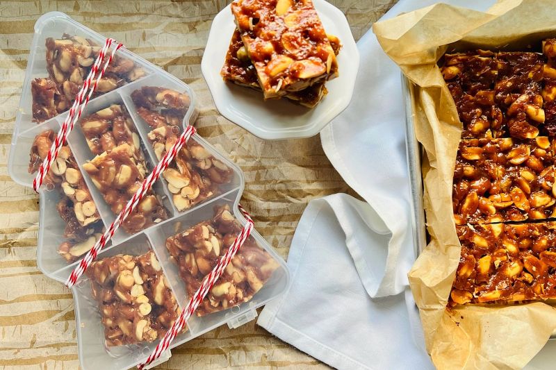An Array of Homemade Peanut Brittle in a Christmas Tree-Shaped Gifting Box, on a Plate and in the Baking Pan