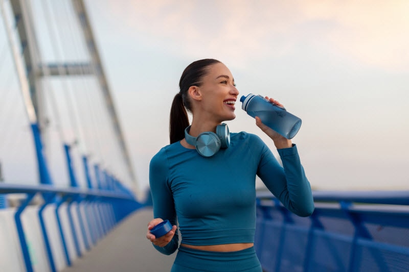 Concept of What is Oxidative Stress Represented by Fit Woman Stopping to Sip From Water Bottle on Dusk-Time Run