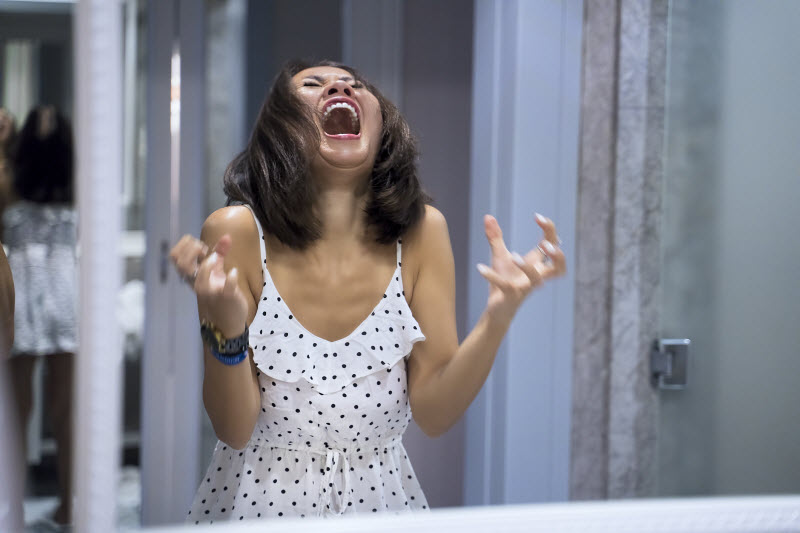 Woman in White Polka Dot Dress with Her Head Titled Back Screaming to Represent Concept of Rage Rooms