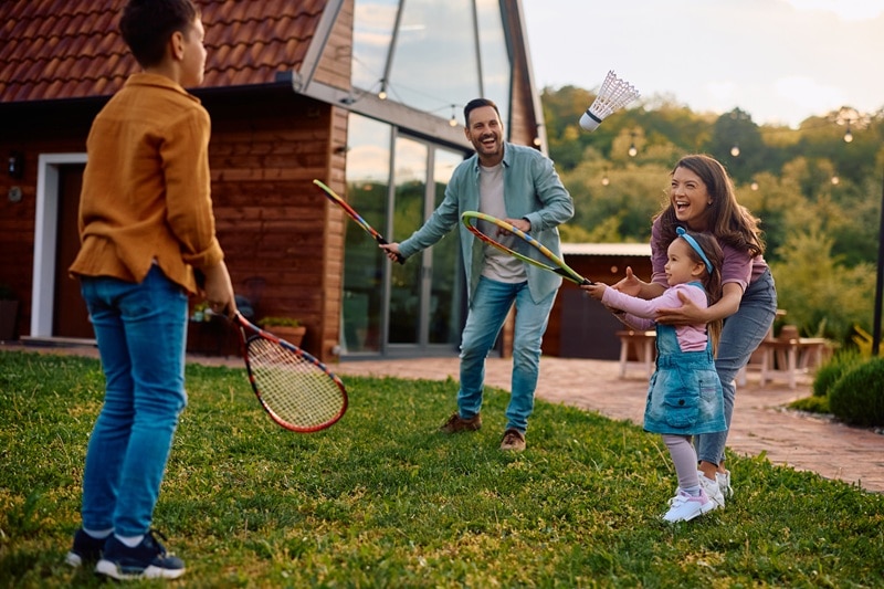 A Family Plays Badminton in Their Front Yard, Representing How Parents Can Have a Positive Influence on Children's Health.