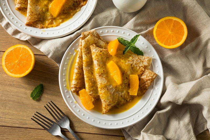 A Plate of Crepe Suzette is Garnished With Sectioned Orange Slices.