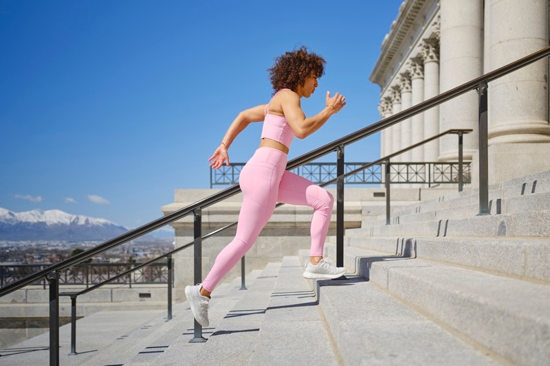 A Woman Runs Up Stairs as Part of a Workout, Representing the Question, "Does Exercise Balance Hormones?"