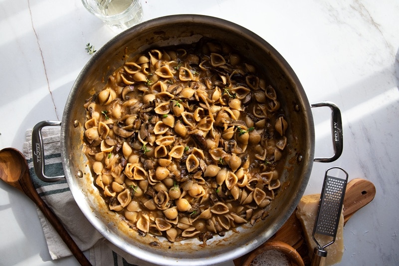 A Large, Deep Pan is Filled With French Onion Pasta Shells and Caramelized Mushrooms.