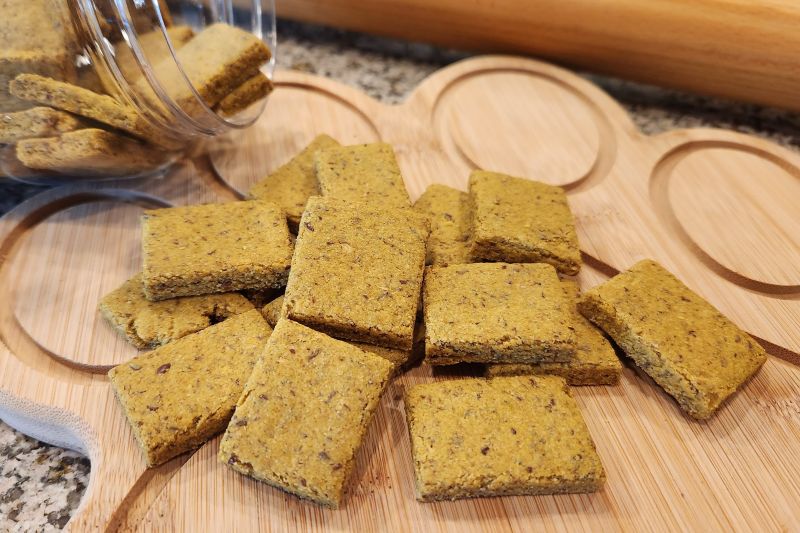 A Scattering of Homemade Pet Treats Made with Fish on a Wooden Paw-Shaped Board