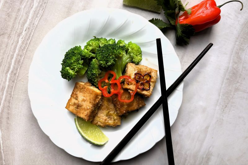 Baked Lemongrass Tofu Cubes on a Plate with Broccoli, Lime and Sliced Red Chili Pepper