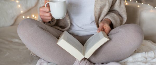 Concept of New Year, New Goals Represented by Woman Reading Book While Holding Mug of Tea