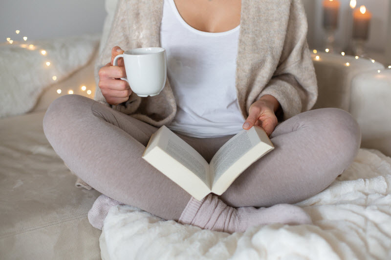 Concept of New Year, New Goals Represented by Woman Reading Book While Holding Mug of Tea