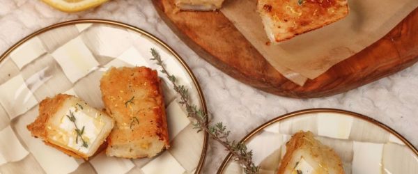 Crispy, flaky phyllo wrapped around warm, tangy feta cheese on appetizer plates, drizzled with honey and sprinkled with flaky salt