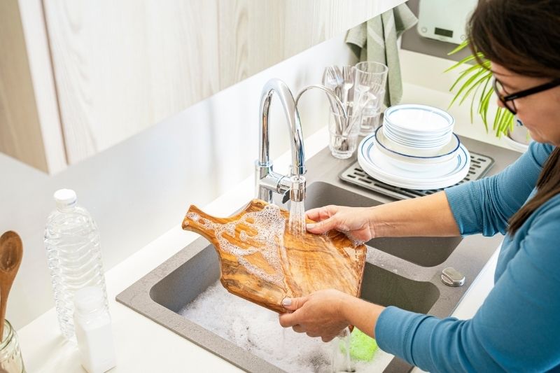 Woman Using Too Much Water Washing Dishes Things That Harm the Environment