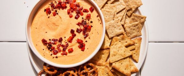 Whipped Feta Pimento Dip_Resized Image_Loren Runion Whipped Feta Dip Topped with Pimentos in a Bowl on a Serving Platter Filled with Crackers and Pretzels