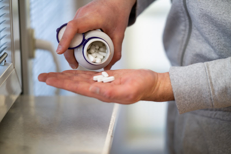 Man Pouring Vitamins into Hand to Represent Concept of High Quality Supplements