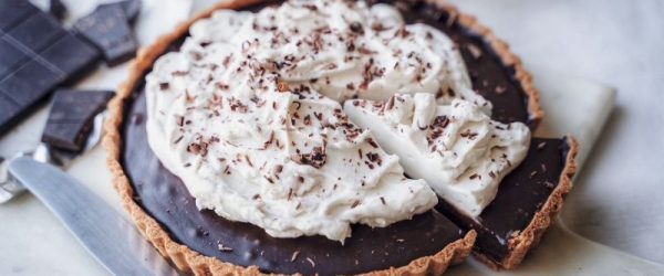 Round Vegan Chocolate Tahini Tart with Cocoa-Almond Gluten-Free Crust and Coconut Cream Whipped Topping Sitting on a Pretty Marble Serving Board