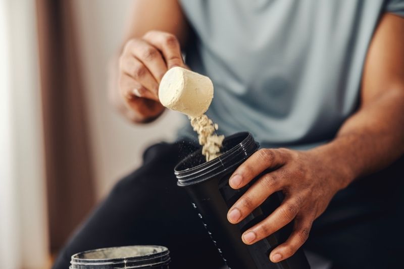 Man Scooping Protein Powder Into Shaker Bottle