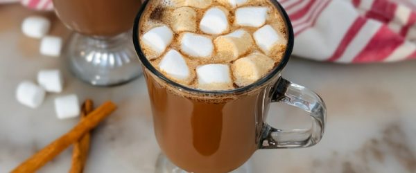 A Glass Mug Is Filled to the Brim With Protein Hot Chocolate and Topped With Mini Marshmallows.