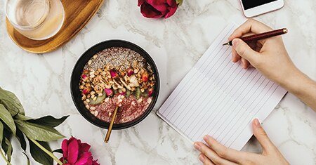 quinoa bowl with person writing in notebook.